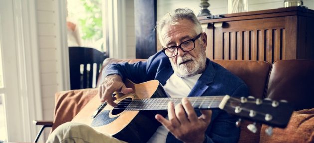 An elderly man is playing guitar